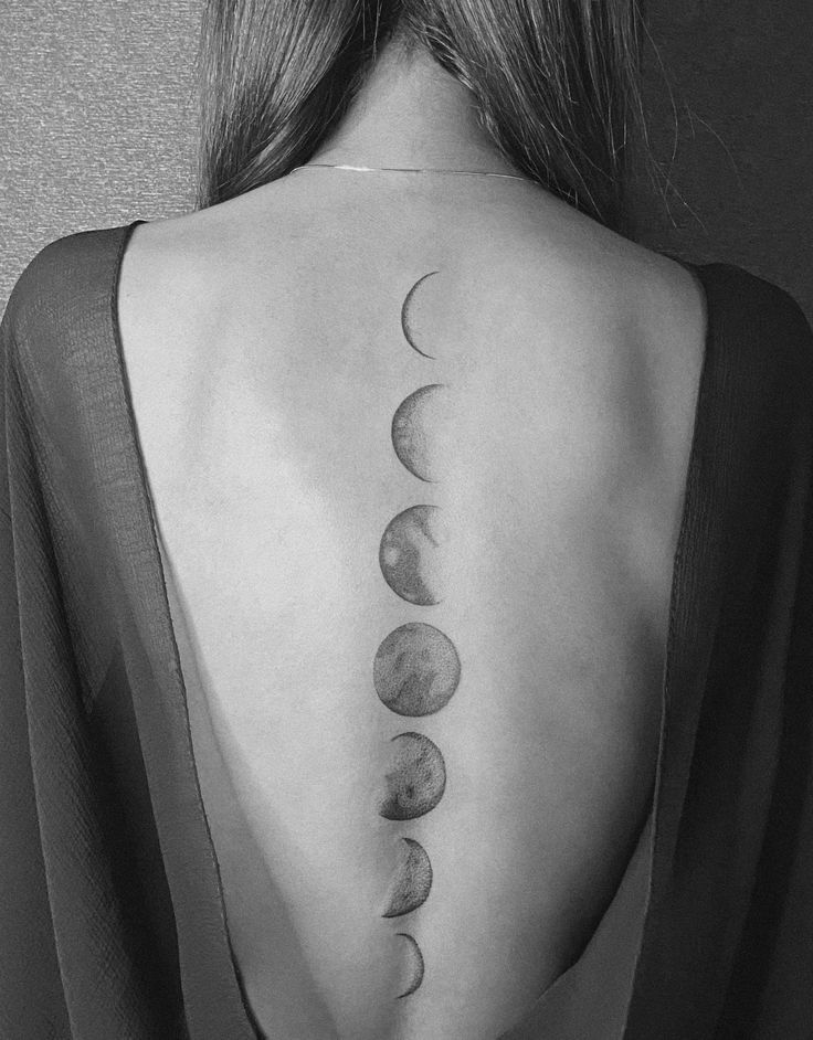 the back of a woman's neck with five phases of the moon on it