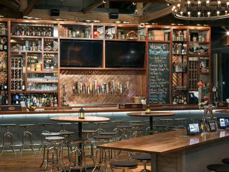 an empty bar with lots of stools and tables in front of the bar area