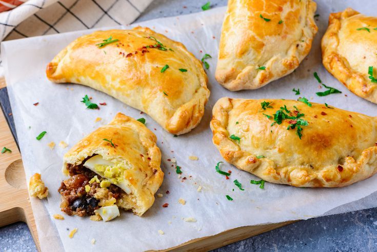 several pastries are sitting on top of a piece of parchment paper with green garnishes