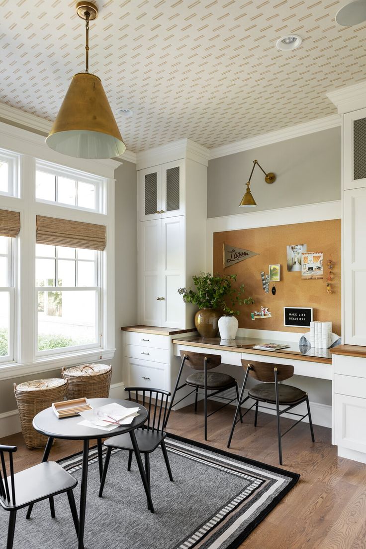 a kitchen with white cabinets and black chairs in front of a table, potted plant on the window sill