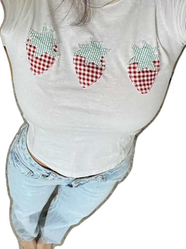 a woman wearing shorts and a white shirt with red checkered strawberries on it