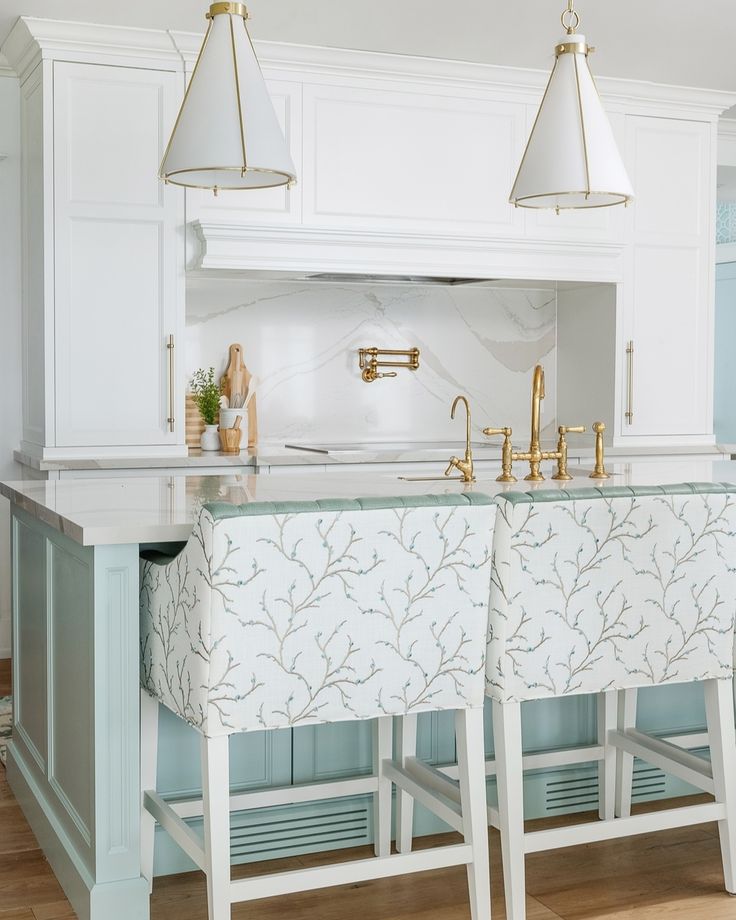 a kitchen island with two stools and lights hanging over the top, in front of an oven