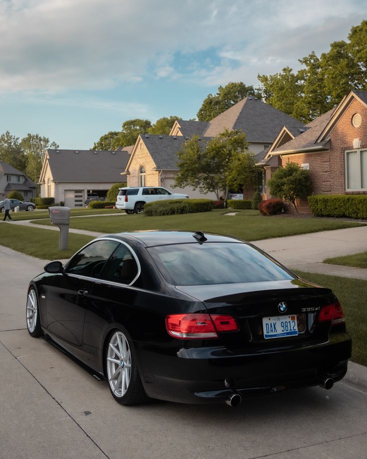 a black car is parked on the side of the road in front of some houses