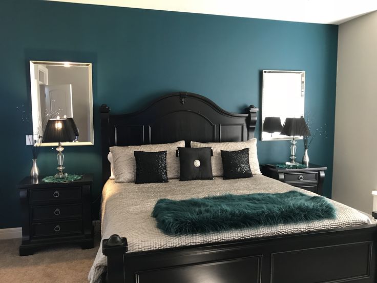 a bedroom with blue walls, black furniture and green fur rugs on the bed