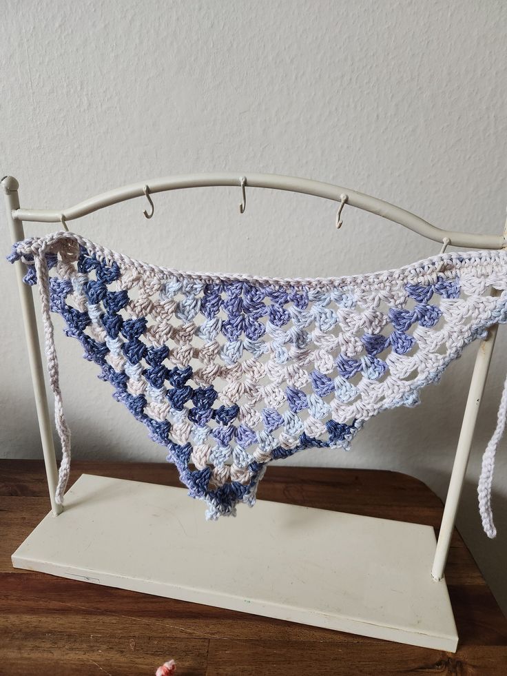 a blue and white crocheted triangle hanging from a hook