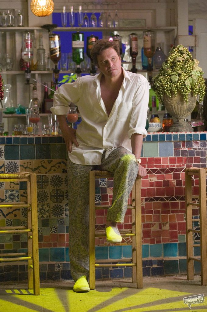 a man sitting on top of a wooden chair in front of a tiled bar area