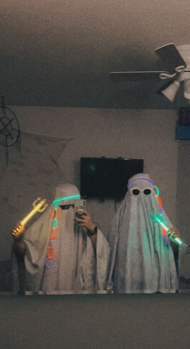 two people dressed in white with glowing lights on their heads and arms, standing next to each other