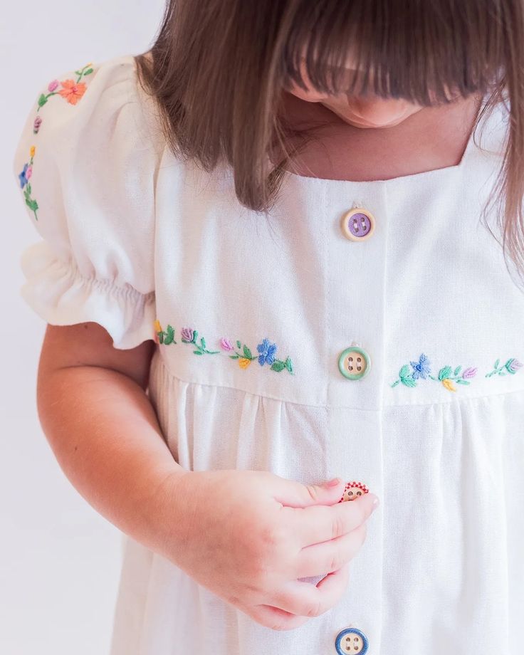 Summer Floral Embroidery Dresses For Playtime, Floral Embroidered Summer Dress For Playtime, Summer Floral Embroidered Playtime Dress, Playful White Embroidered Dress, Cotton Dress With Floral Embroidery For Playtime, Playful Cotton Dresses With Buttons, Cotton Dresses With Buttons For Playtime, Cute Floral Embroidery Dress For Playtime, White Button-up Dress For Dress-up Occasion