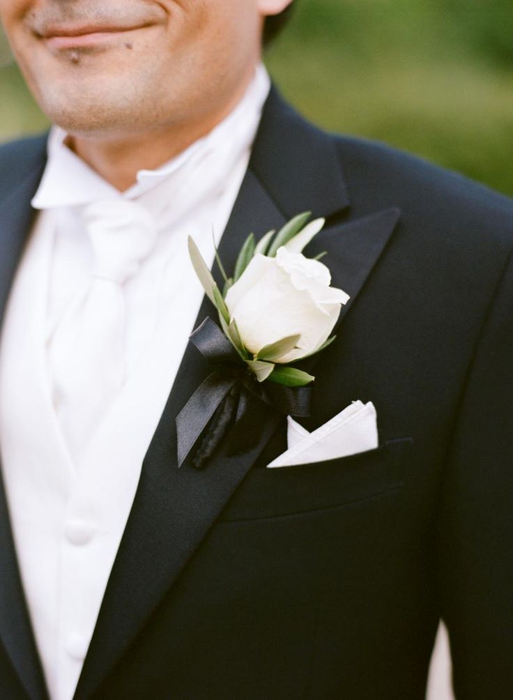 a man in a tuxedo with a white rose on his lapel flower