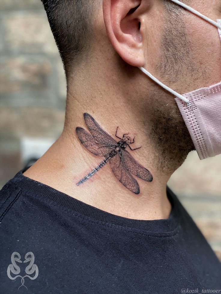 a man wearing a face mask and neck tattoo with a dragonfly on his neck