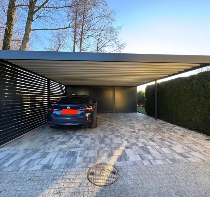 a car is parked in the driveway next to a garage with an attached carport