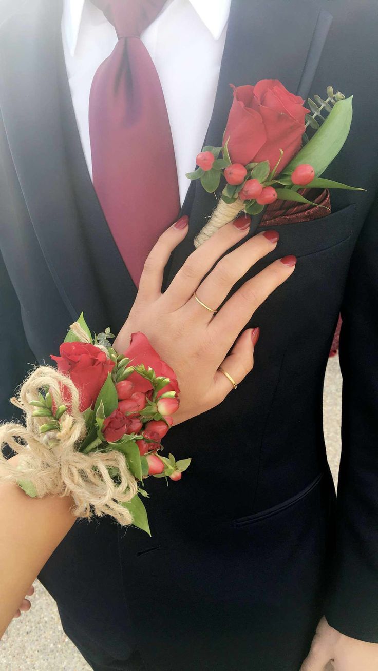 a person wearing a suit and tie holding flowers in their hands with one hand on the other