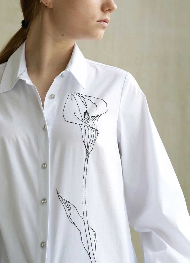 a woman wearing a white shirt with a flower drawn on it