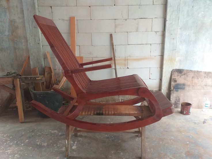 a wooden chair sitting on top of a floor next to a white brick wall in an unfinished room