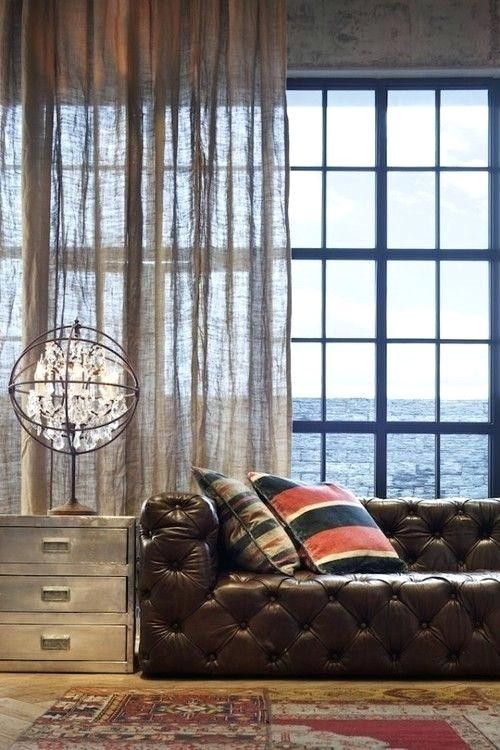 a brown leather couch sitting in front of a window