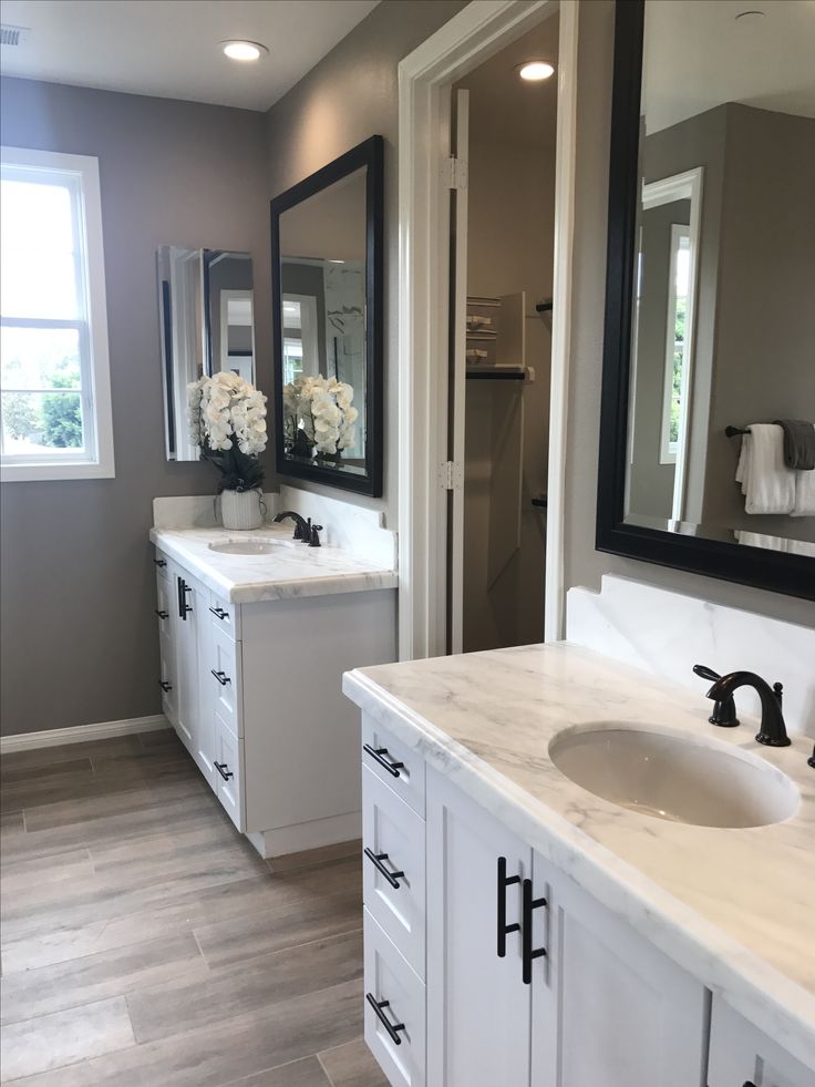 a large bathroom with two sinks and mirrors on the wall, along with white cabinets