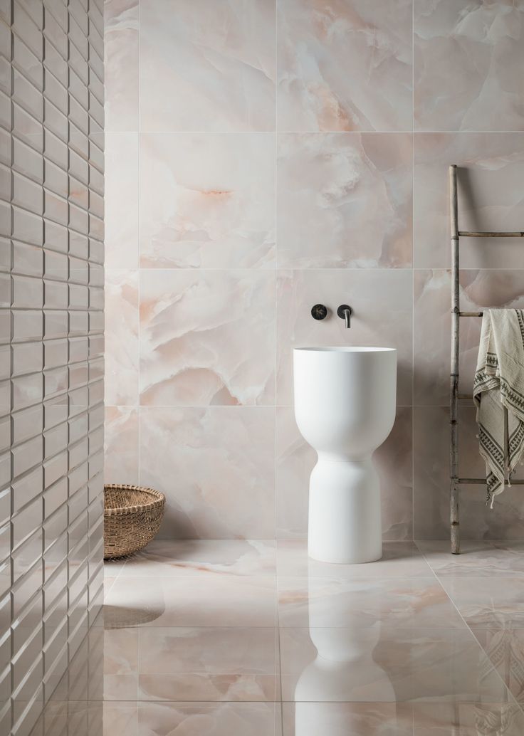 a white toilet sitting in a bathroom next to a wall mounted faucet and tiled walls