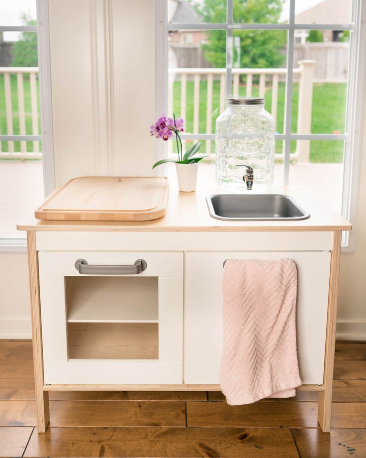 a kitchen with a sink, counter and window in the backround that has flowers on it