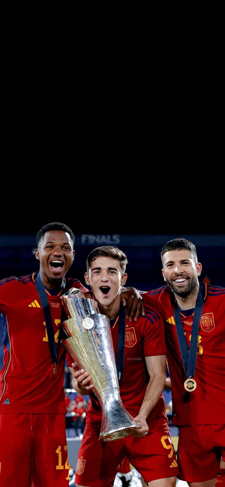 three men in red soccer uniforms holding a silver trophy