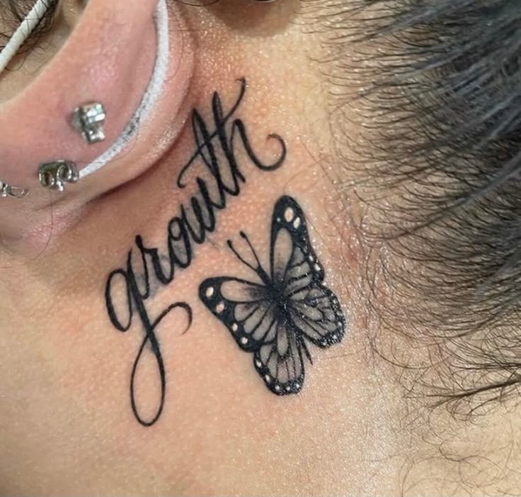 a woman's behind the ear tattoo that says strength and a butterfly on it