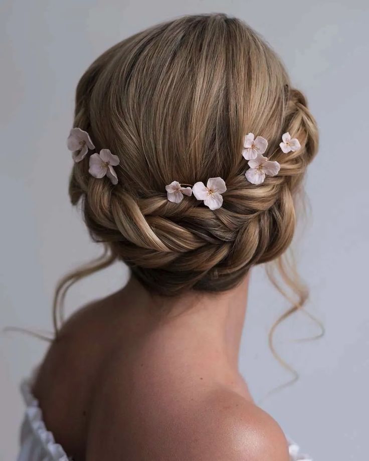 a woman with blonde hair and flowers in her hair is wearing a wedding hairstyle