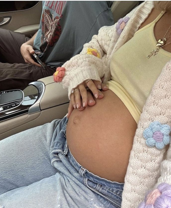 a pregnant woman sitting in the back seat of a car with her hand on her belly