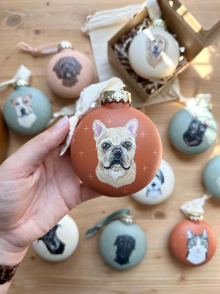 a hand holding an ornament with a dog's face painted on it