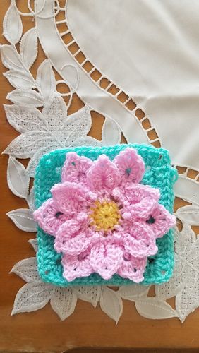 a crocheted flower is on top of a doily