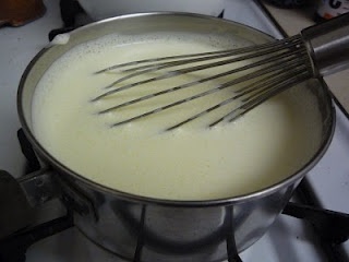 a metal pot filled with liquid and whisk on top of a gas stove