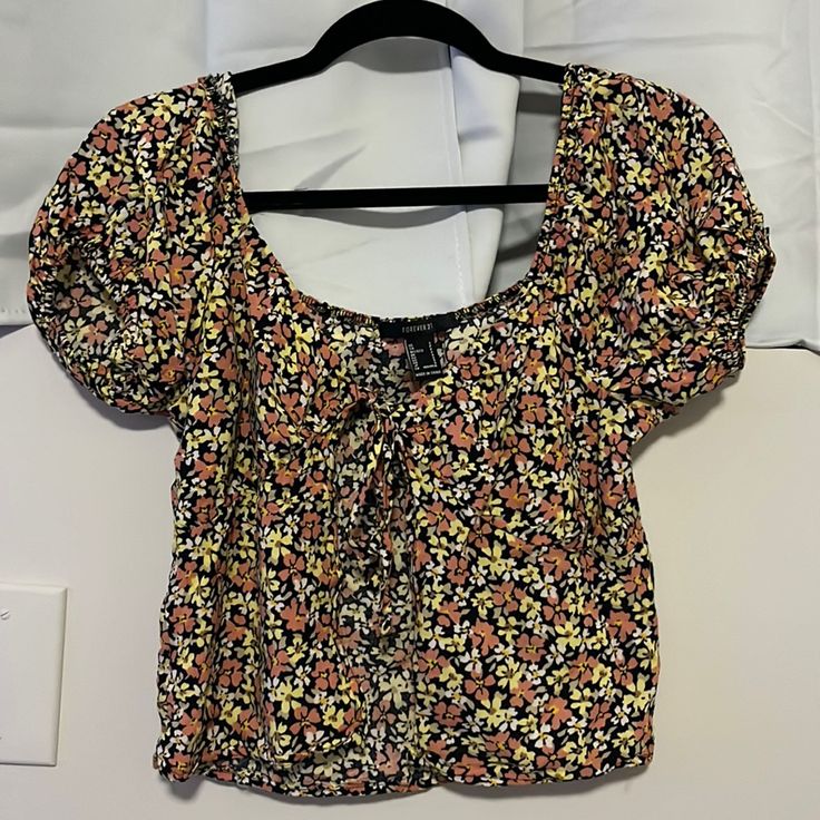 New Without Tags. Shirt Is Black With Pink, Yellow And White Flowers. Shirt Is Open From The Front, You Can Untie And Adjust To Your Liking. Sleeves Are Rouched As Well. Floral Print Short Sleeve Crop Top For Day Out, Cute Black Floral Print Tops, Casual Floral Print Crop Top For Day Out, Floral Print Crop Top Blouse For Day Out, Floral Crop Top Blouse For Day Out, Forever 21 Black Floral Print Top, Forever 21 Floral Print Cotton Crop Top, Forever 21 Floral Print Cotton Tops, Forever 21 Floral Print Crop Top