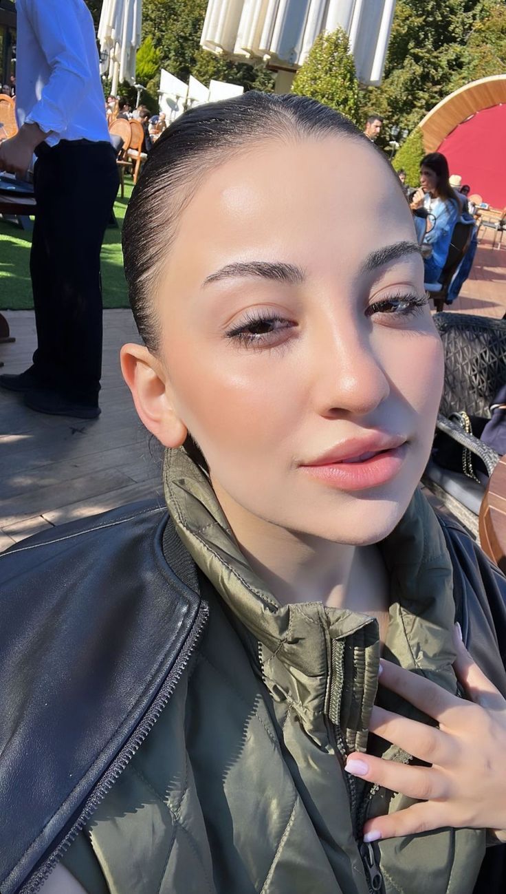 a woman in a leather jacket is posing for the camera with her hand on her shoulder