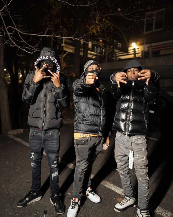 three young men standing next to each other in the street with their hands on their hipss