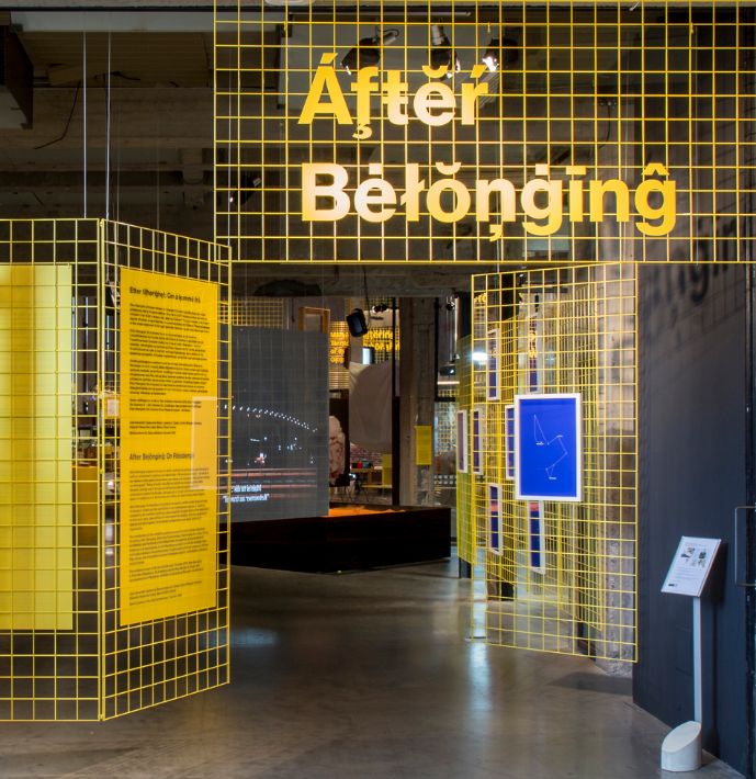 the entrance to an office building with yellow and black tiles on the walls that read after belonging