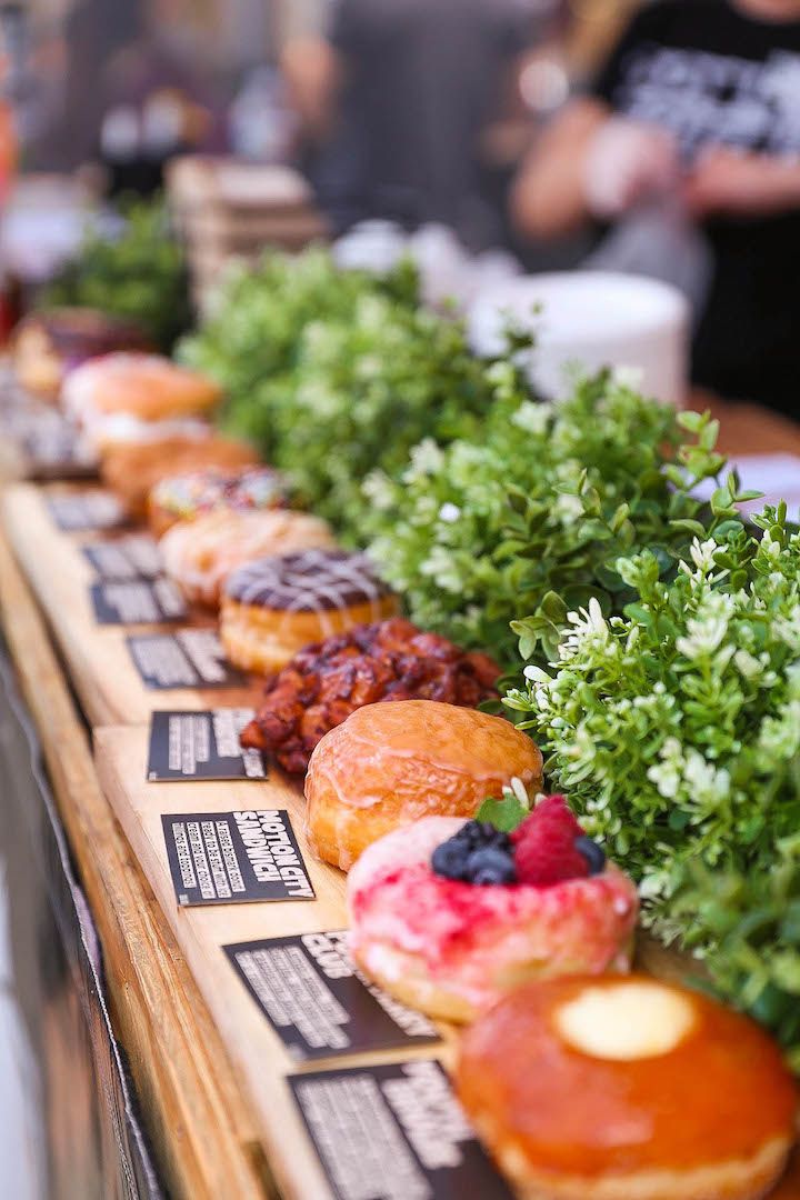 there are many different types of donuts on the long table, each with toppings