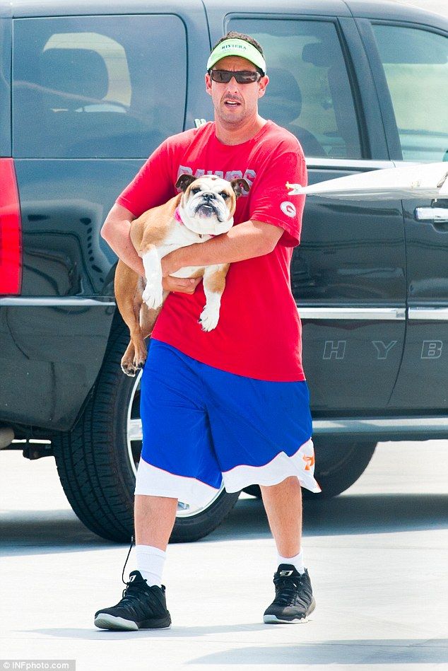 a man holding a dog in his arms while standing next to a black pickup truck