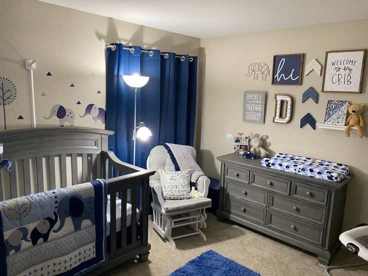 a baby's room with blue and gray decor on the walls, crib bedding and dressers