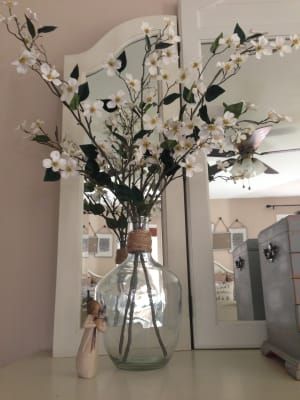 a vase filled with white flowers sitting on top of a table next to a mirror