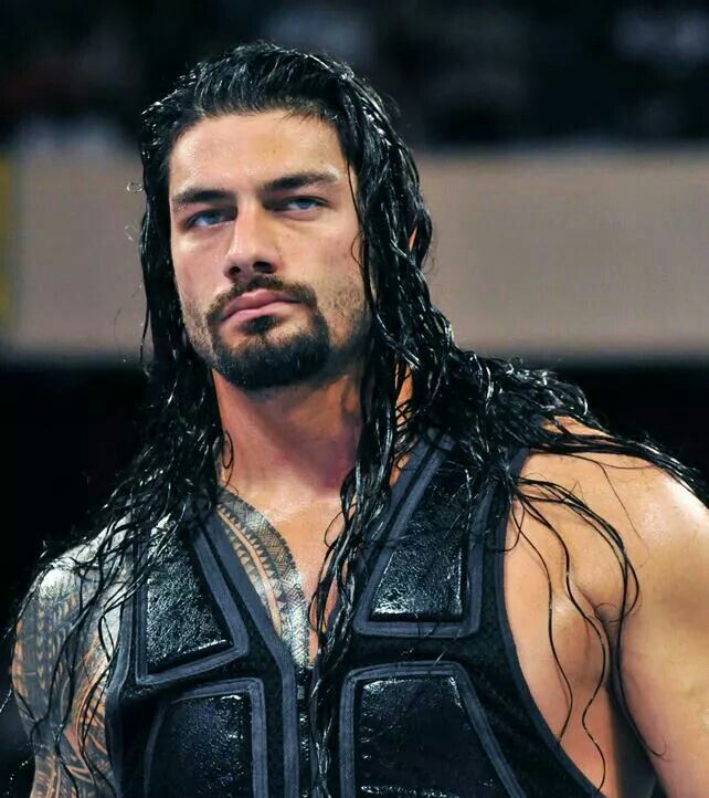 a man with long hair and no shirt on standing in front of a crowd wearing a leather vest