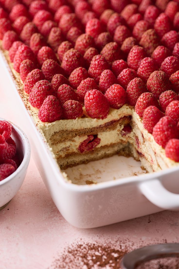 a cake with raspberries on top is cut in half and ready to be served