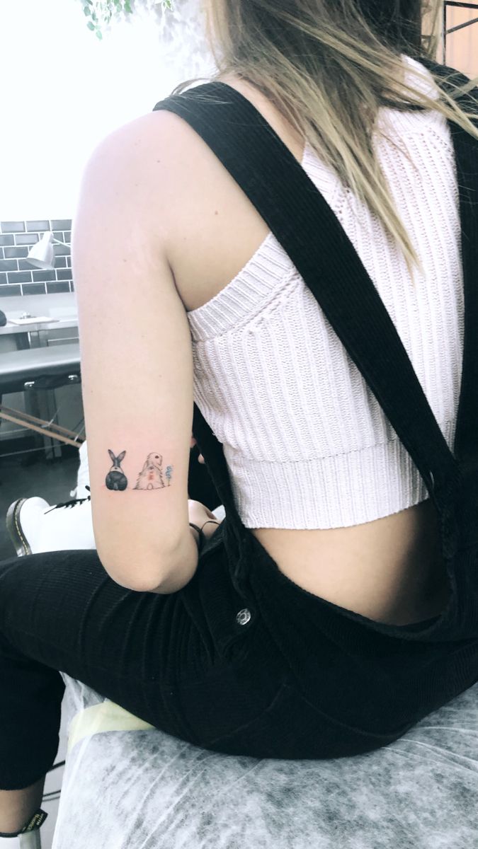 a woman sitting on top of a bed with her back turned to the camera and tattoos on her arm