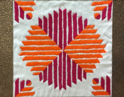 an orange and pink design on white fabric with red accents in the center, sitting on a brown surface