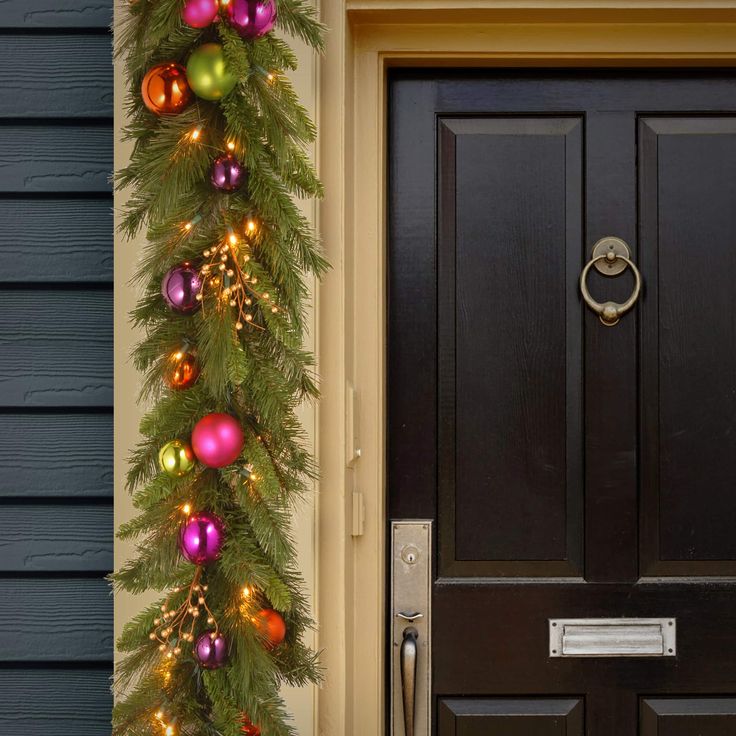 a christmas garland on the front door of a house decorated with ornaments and baubles