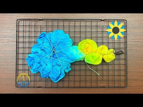 a blue and yellow umbrella sitting on top of a wire rack next to a sunflower