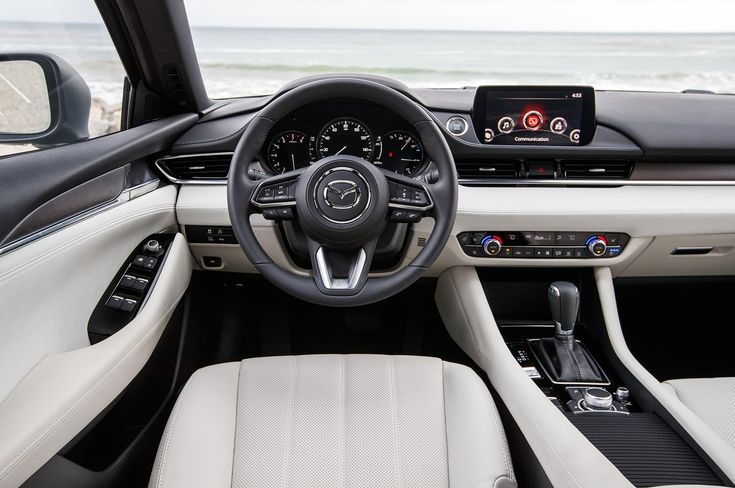 the interior of a car with dashboard, steering wheel and touchscreens on an ocean beach