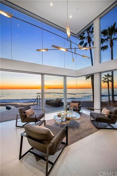 a living room with large windows overlooking the ocean and palm trees in front of it