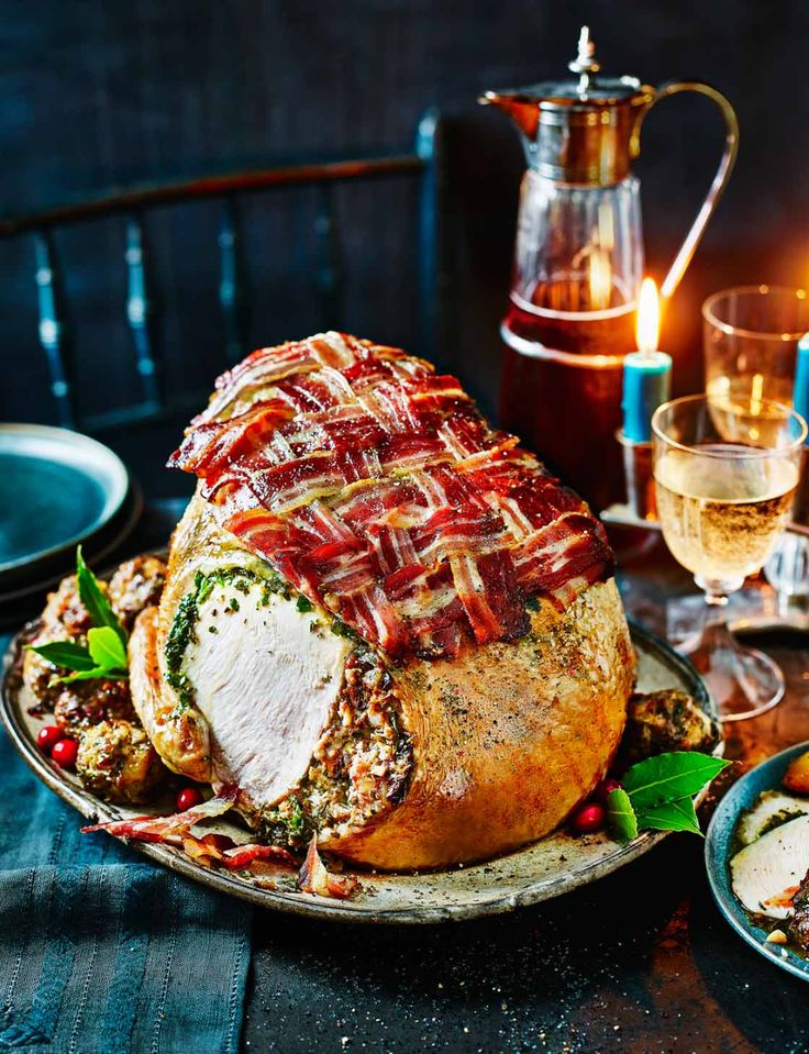 a large meatloaf on a platter next to some wine glasses and food