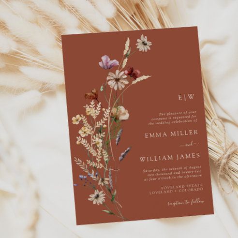 a wedding card with flowers on it sitting next to some dried grass and wheat stalks