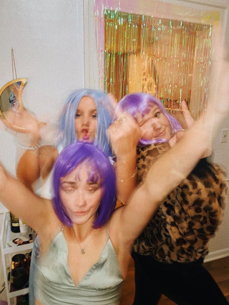 three women with purple hair are posing for a photo in front of a mirror and holding their hands up