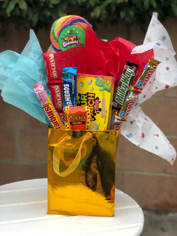 a gold bag filled with candy and candies on top of a white table next to a brick wall