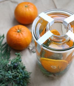 two oranges sitting next to a glass jar filled with liquid and cut in half